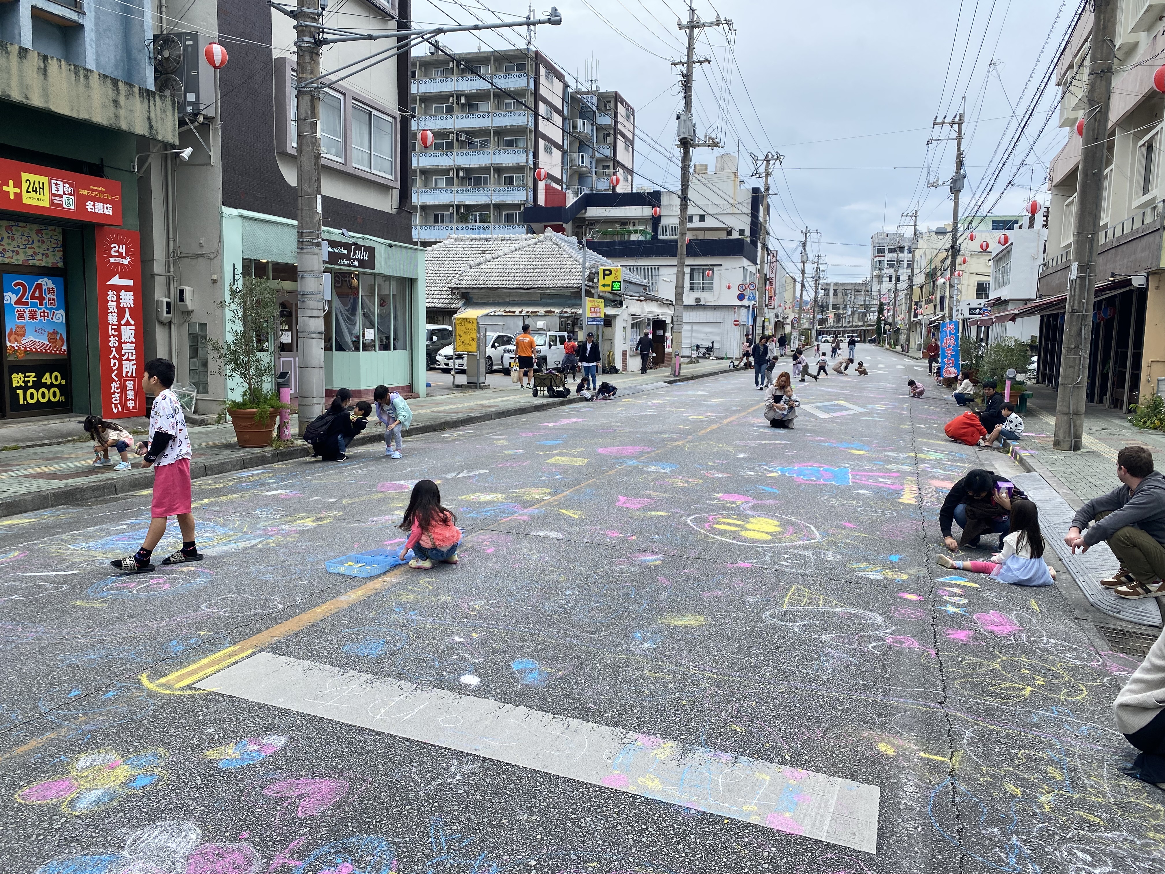 路上チョークで遊ぶ子どもたちと住民